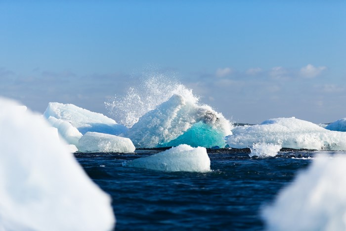 Icebergs Splashing in the Ocean Under a Blue Sky
