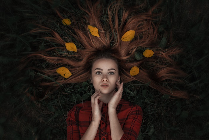 Woman with long red hair and freckles lying down