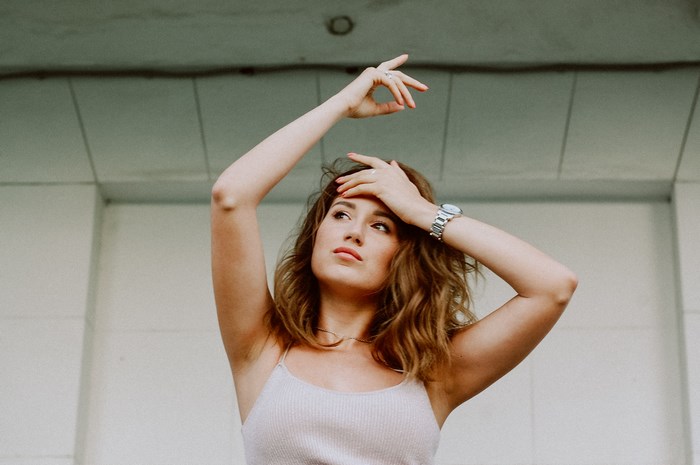 Woman with hands in hair wearing a tank top and watch