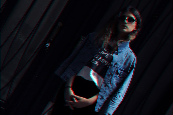 Woman in denim jacket and crop top with sunglasses