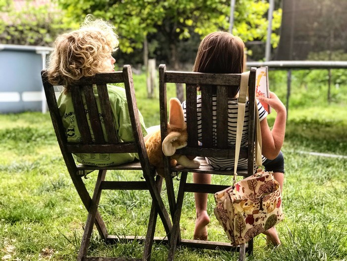 Two children reading books in a backyard