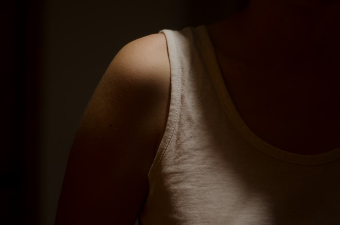 Woman's shoulder and tank top in shadow
