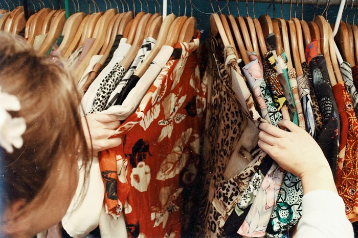 Woman browsing clothes on hangers in a retro store
