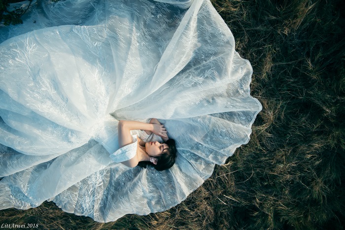 Woman in a white dress lying on grass
