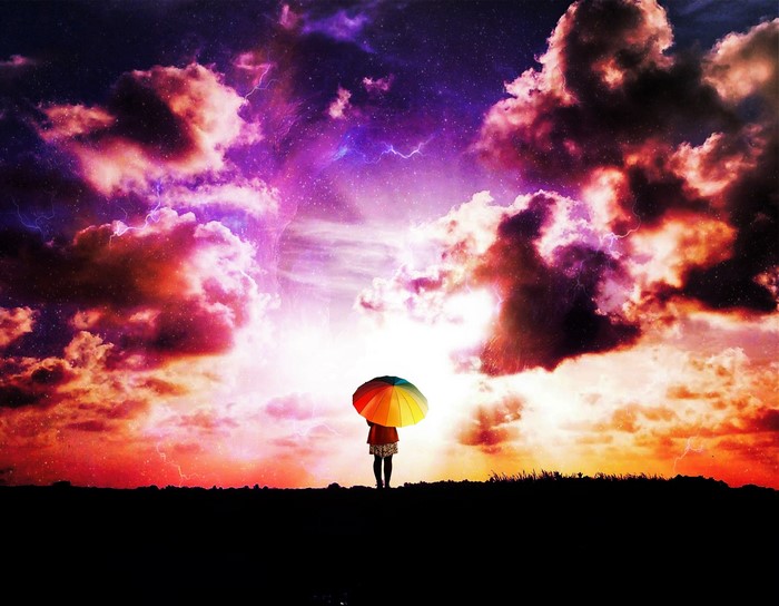 Girl with colorful umbrella under stormy sky