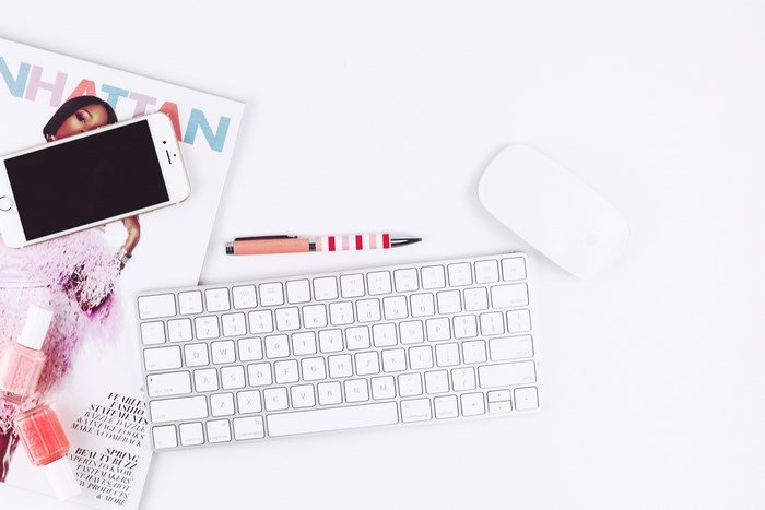 Flat lay of Apple keyboard, mouse, phone, and nail polish