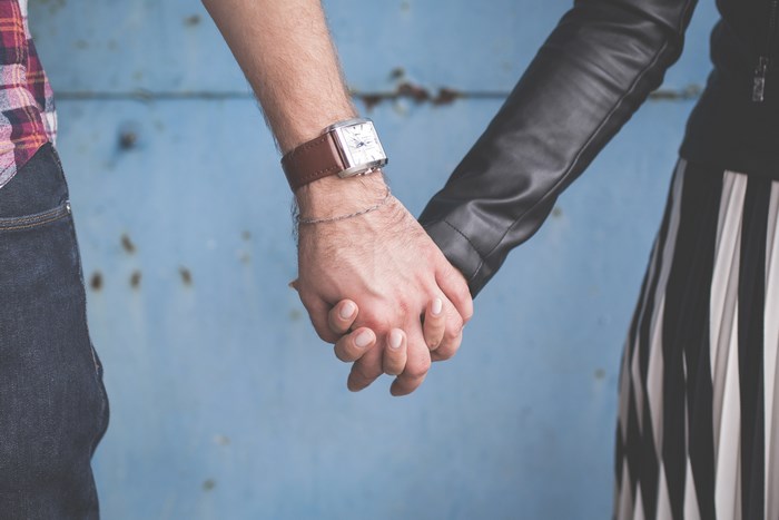 Couple holding hands in front of a blue wall