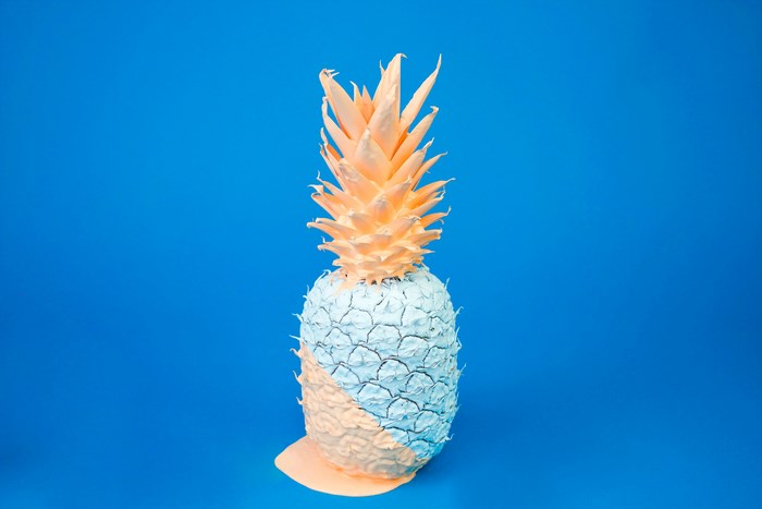 Painted pineapple with dripping paint on blue background