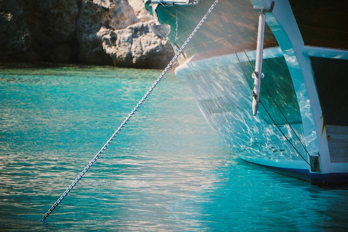 Ship's anchor chain in turquoise water near rocks