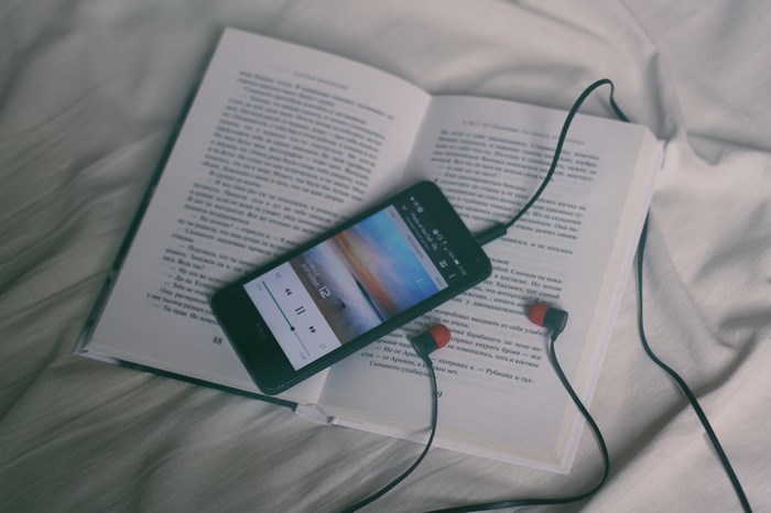 Smartphone with headphones on an open book
