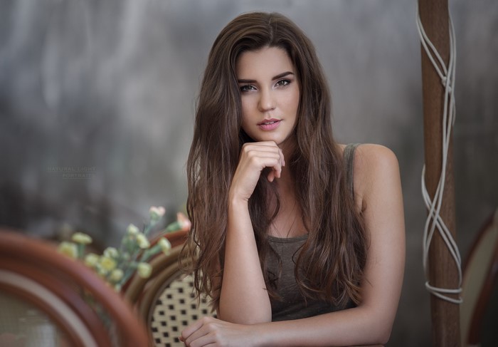 Brunette woman with long hair resting chin on hand