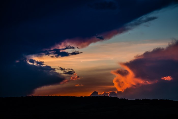 Moody sunset with colorful clouds over a dark silhouette