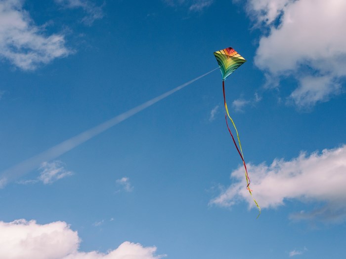 A colorful kite flying in a blue sky with clouds