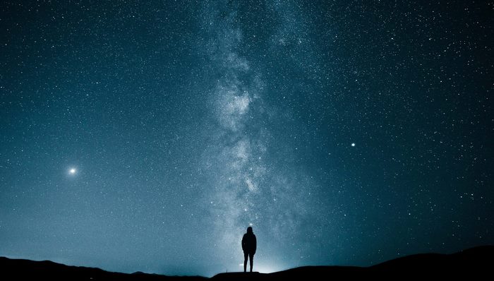Person standing under the Milky Way galaxy