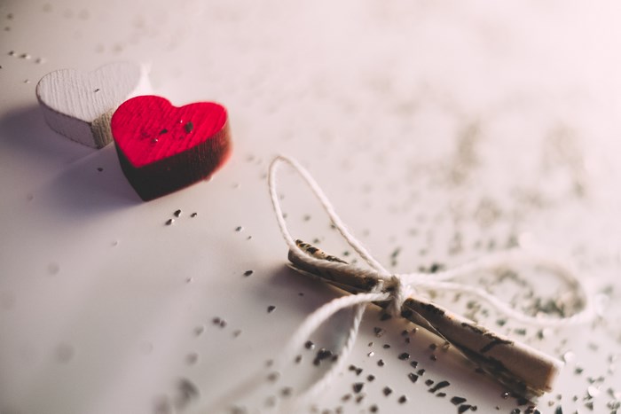 Two wooden hearts and a rolled message tied with string
