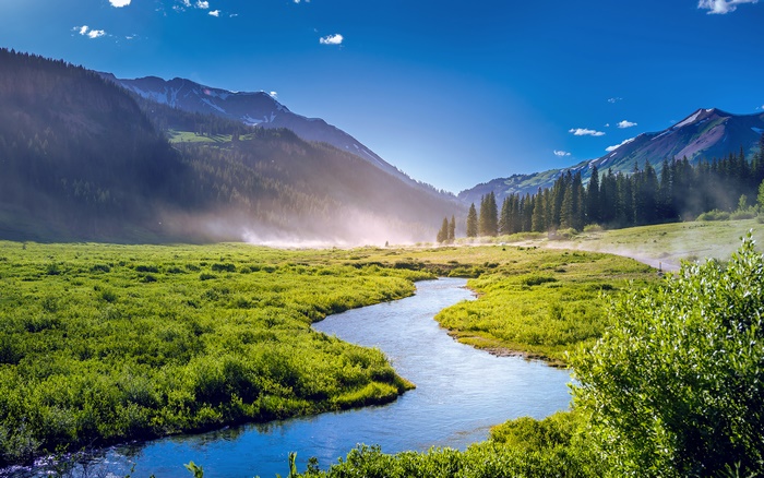 River flowing through a green valley with mountains in Colorado