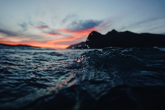 Wave crashing at sunset with mountains in Malibu