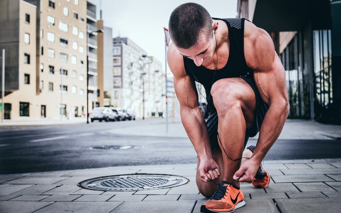Man tying shoelaces on sneakers in urban setting