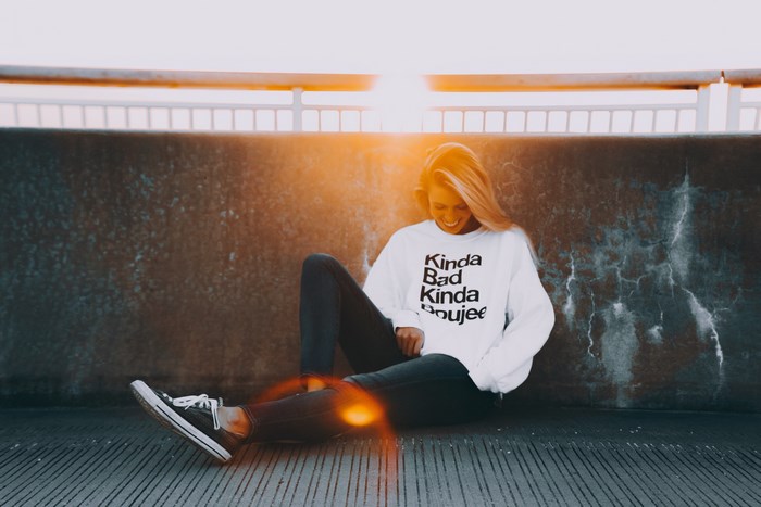 Woman wearing a white sweatshirt with a slogan