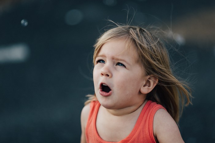 A young girl with blonde hair looks up in surprise
