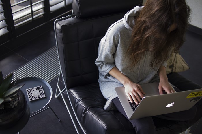 Woman working on a MacBook in a leather chair