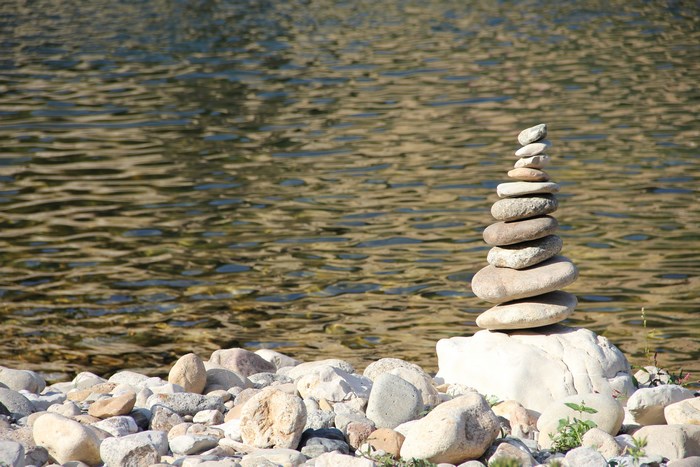 Stack of balanced stones on a rocky shore by a river