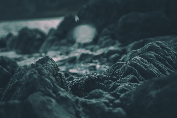 Close up of dark, wet rocks near water