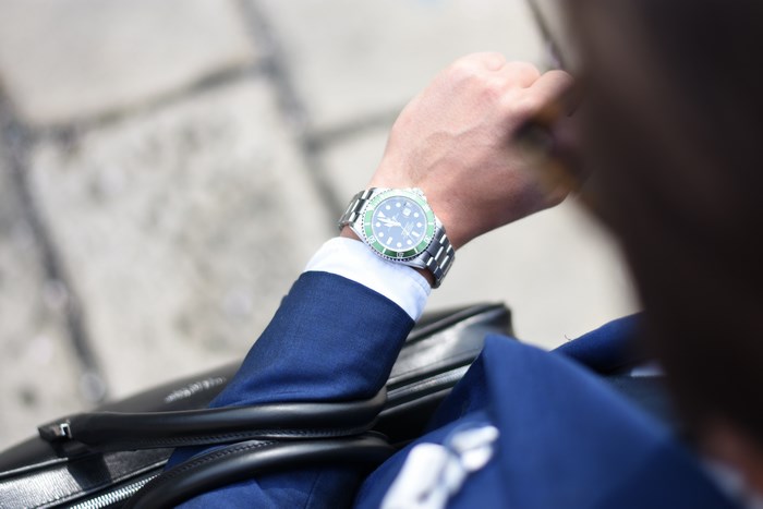 Man in blue suit checking Rolex watch
