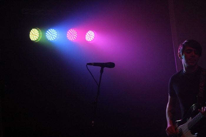 Musician playing guitar under colorful stage lights