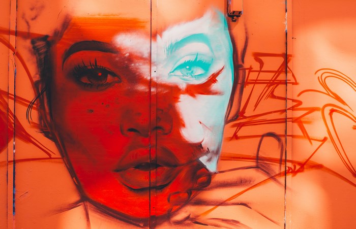 Graffiti art of a woman's face on an orange wall