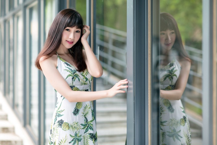 Asian woman in a tropical dress by a window