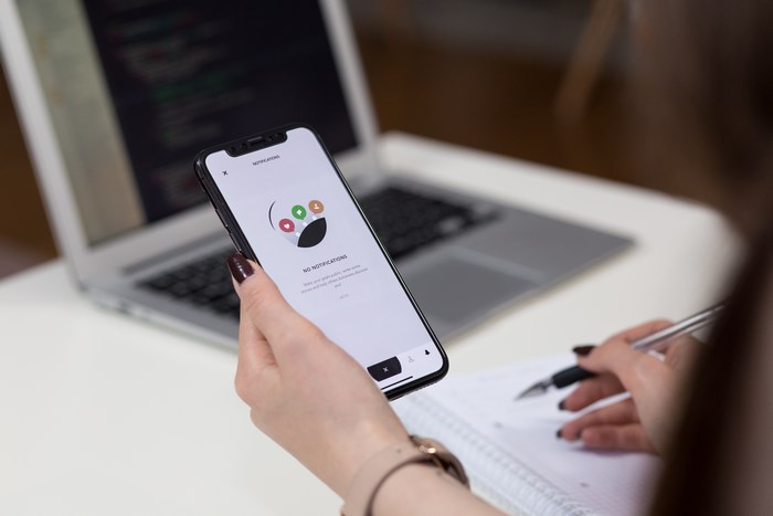 Woman holding iPhone X with 'No Notifications' app screen
