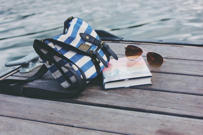 Striped bag, book, and sunglasses on a dock