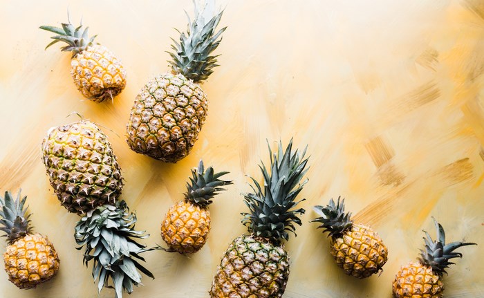 Several pineapples scattered on a yellow background