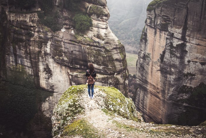 Woman standing on a rocky cliff edge in Greece