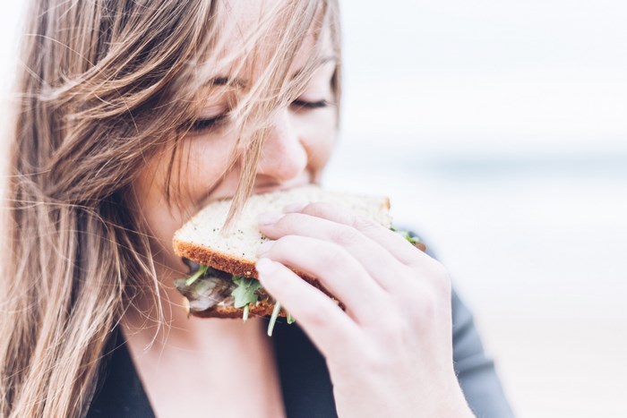 Woman eating a sandwich outdoors on a windy day