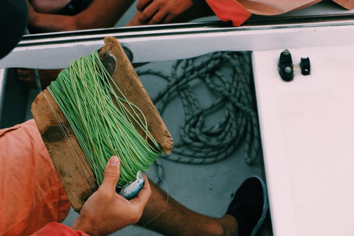 Person holding fishing line and lure on a boat