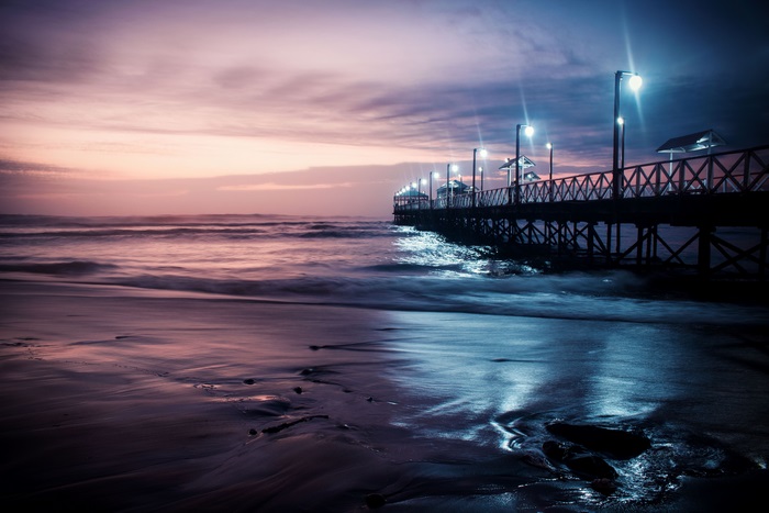 Pier with lights over the ocean at dusk