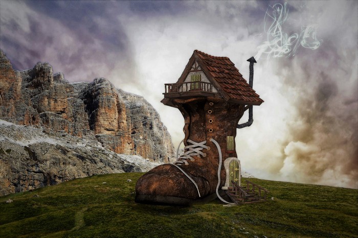 Fantasy shoe house on a grassy hill with mountains
