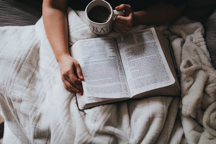 Person reading a Bible with a cup of coffee