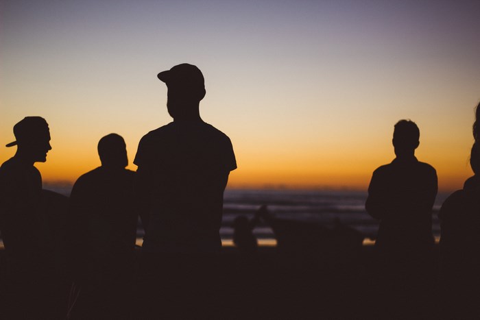 Group of friends silhouetted against a sunset on the beach