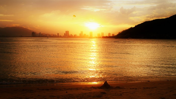 Sunset over the sea with a city skyline and mountains