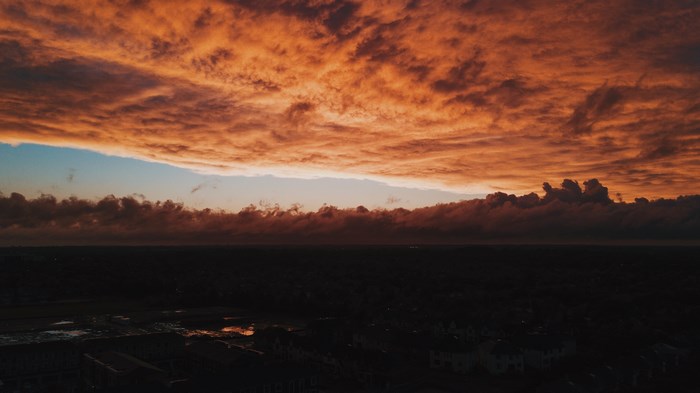 Orange clouds at sunset over a dark landscape