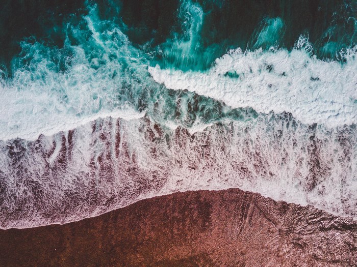 Aerial view of ocean waves crashing on a rocky shore