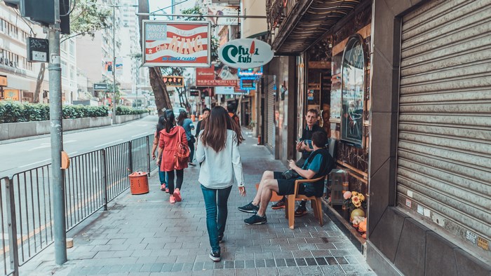 People walking on a city street with shops and signs