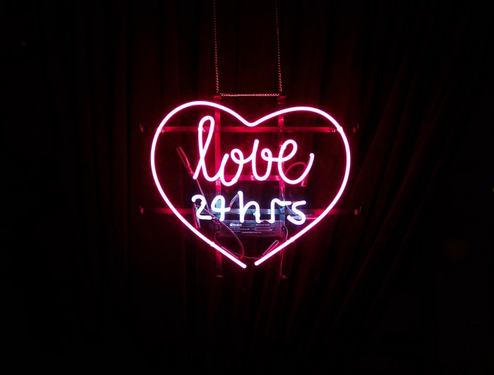 Pink neon heart sign with "love 24hrs"