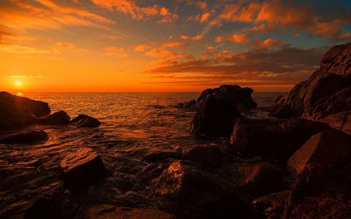 Sunset over the ocean with rocky shore