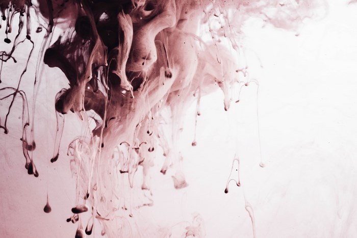 Mauve and pink ink swirls in water