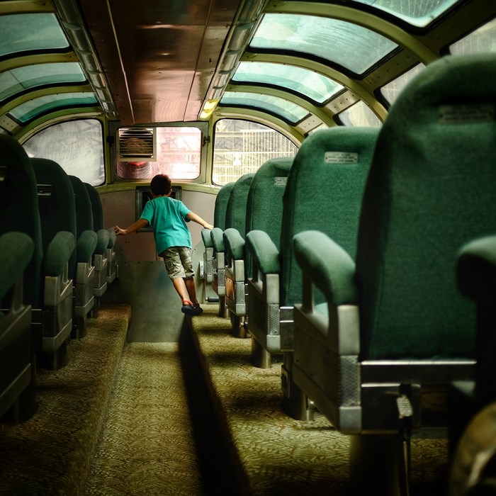 Boy walking down a vintage train aisle with glass dome ceiling