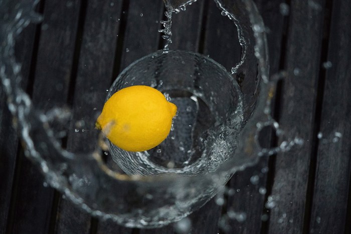 Lemon splashing into a glass on a wooden table